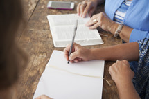 women at a Bible study writing in journals and discussing scripture 