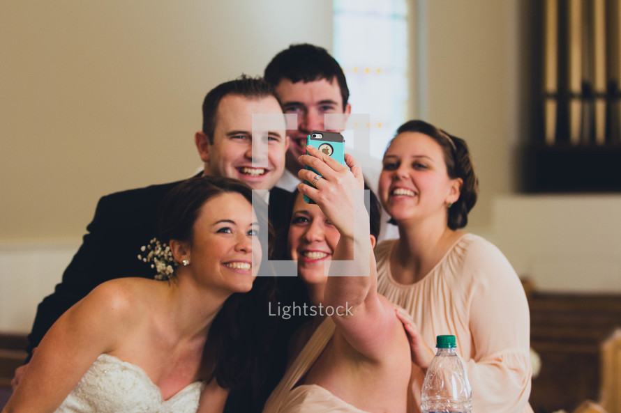 bridesmaids, groomsmen, bride, and groom taking a selfie 