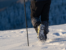 Close up of a man hiking on a mountain covered on snow, in boots with shoe skpikes. Outdoor winter trekking