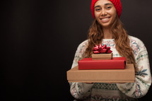 a woman holding a stack of Christmas gifts 