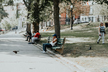 people sitting on park benches in a city park 