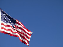 An American flag flying against a blue sky.