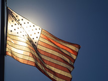 Sun shining through an American flag.