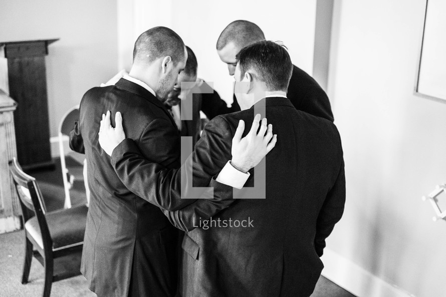 groomsmen praying before a wedding 