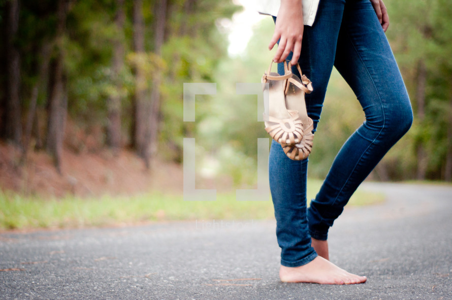 bare foot woman holding her shoes 