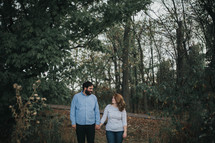 a couple holding hands outdoors, in fall 