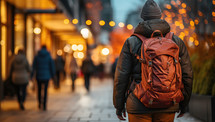 Back view of a young man with a backpack walking in the city at night