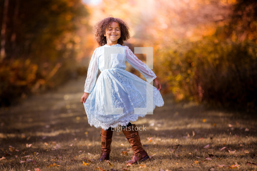 a little girl in a dress standing outdoors in fall 