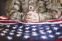 serviceman praying over an American flag 