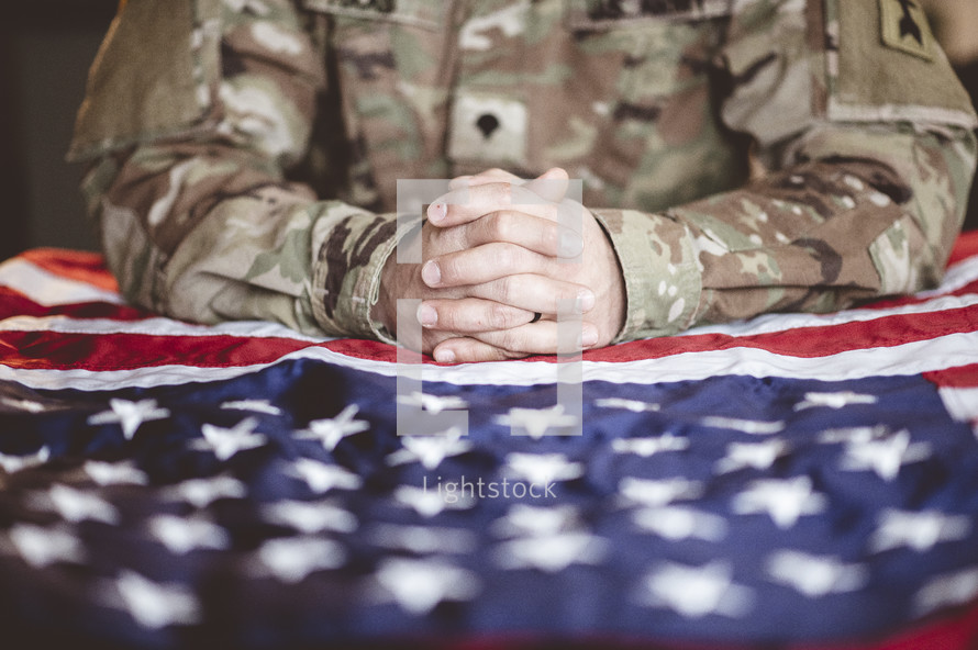 serviceman praying over an American flag 