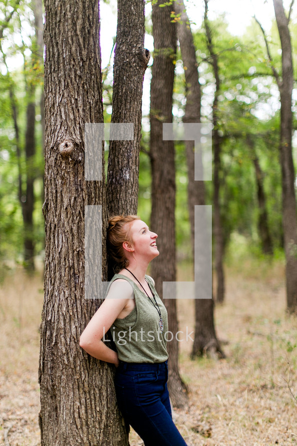 woman leaning on a tree in a forest 