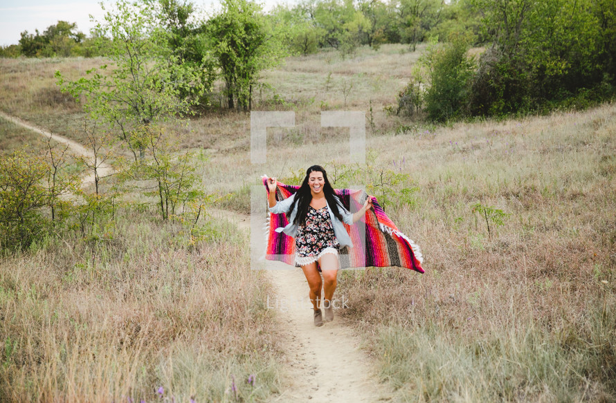 woman wrapped in a blanket walking up a hill 