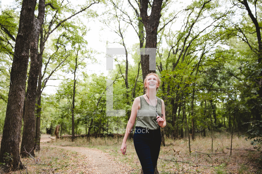 a woman walking on a trail through a forest 
