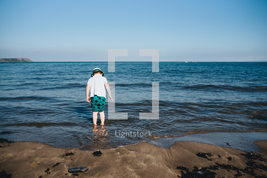 a boy standing in the ocean 