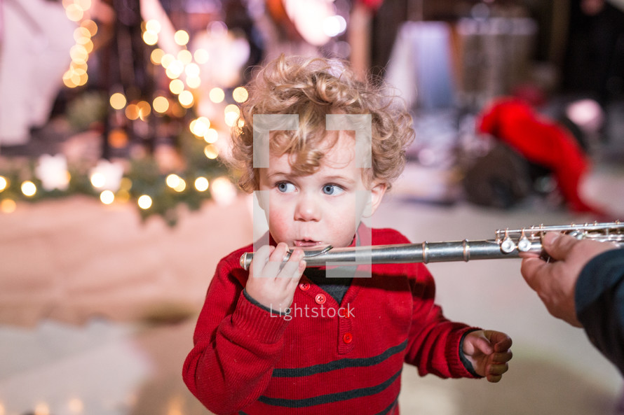 toddler boy blowing into a flute 