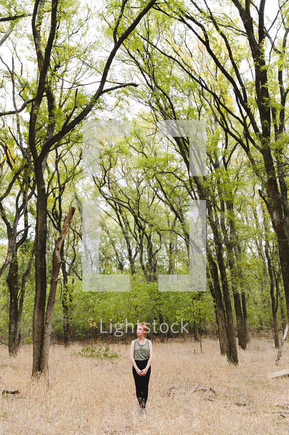 woman standing outdoors alone in a forest 
