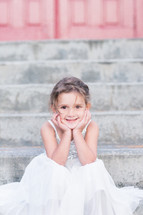 a little girl in a dress sitting on steps 