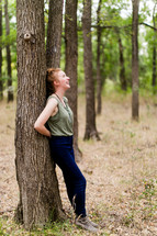 woman leaning against a tree in a forest 