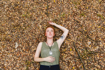 a woman lying on the ground in fall leaves 