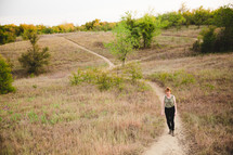 woman walking on a path up a hill 