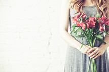 Pregnant woman holding bouquet of flowers.