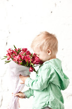 Boy smelling bouquet of flowers,