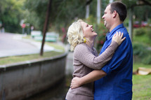 Couple embracing , standing in a park by a street