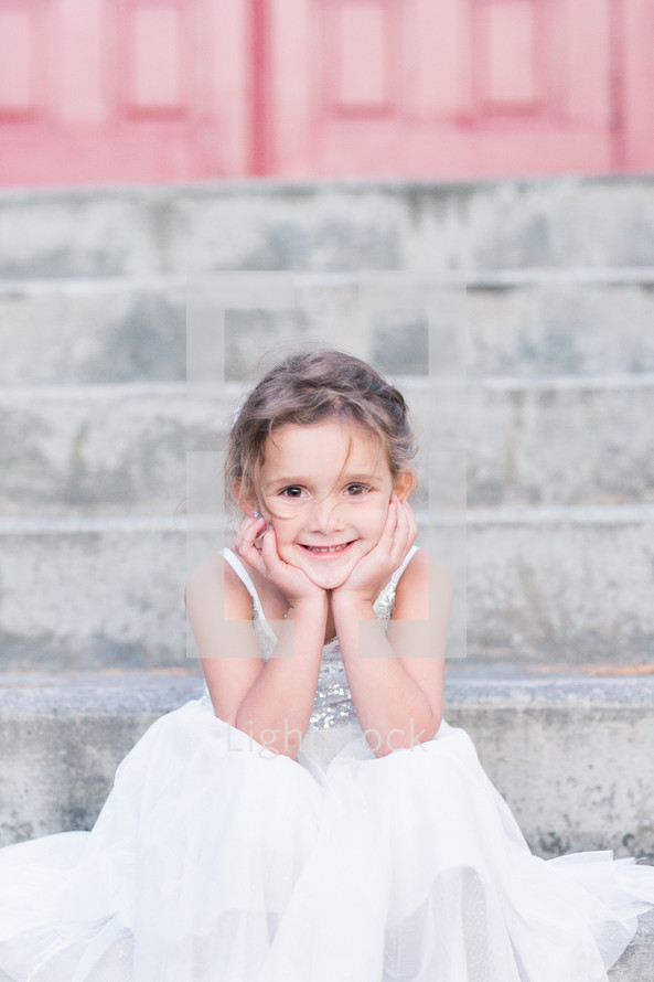 a little girl in a dress sitting on steps 
