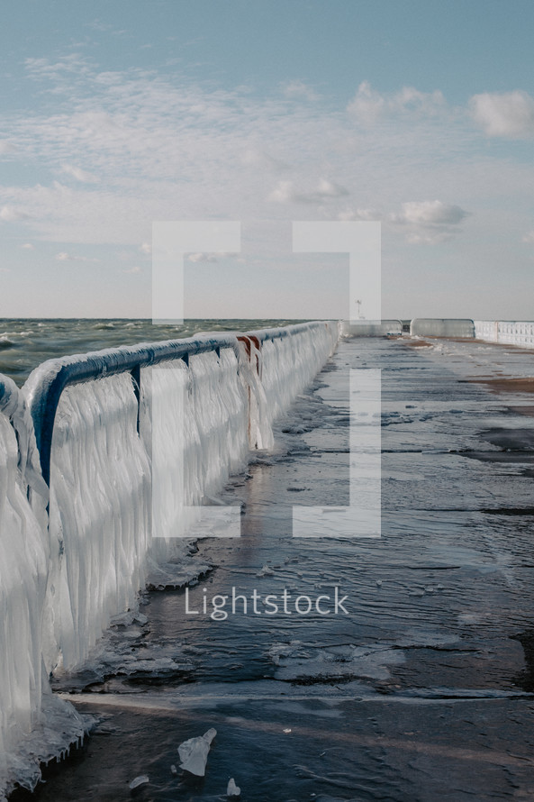 Ice covered railing on beach pier on Lake Michigan