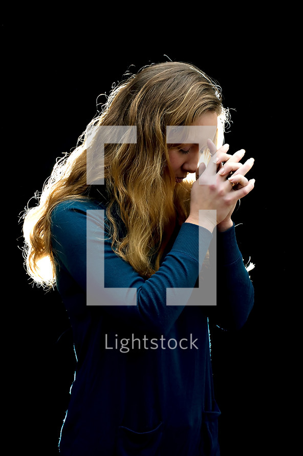 woman with head bowed in prayer and praying hands 