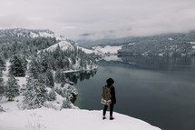 a woman standing at the edge of a snowy cliff 
