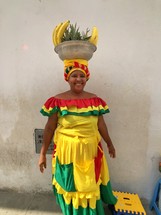 a woman balancing fruit in a bowl on her head 