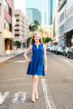 woman in a blue short dress standing in the middle of a road 