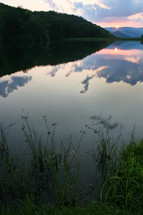 reflections of clouds on lake water at sunset 