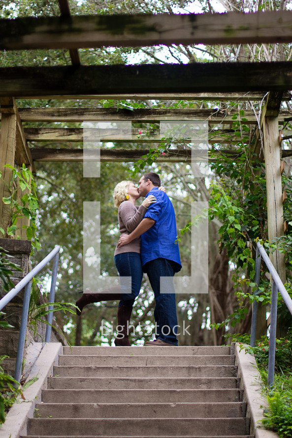 A couple kissing under an arbor.