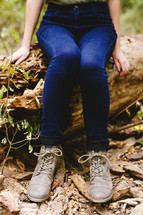 woman's legs and shoes as she sat on a log