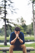 a man sitting outdoors praying 
