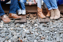 legs of a family sitting on train tracks 