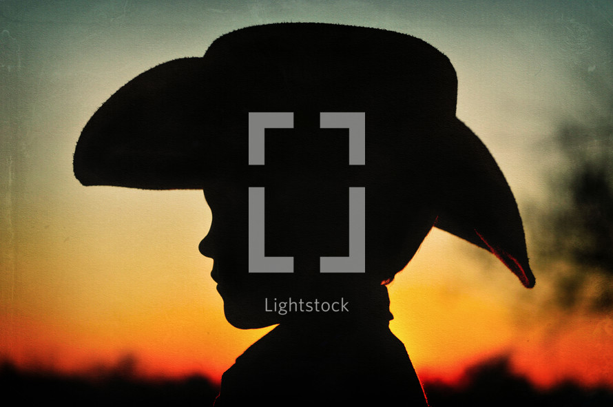 A silhouette of a young boy in a cowboy hat.