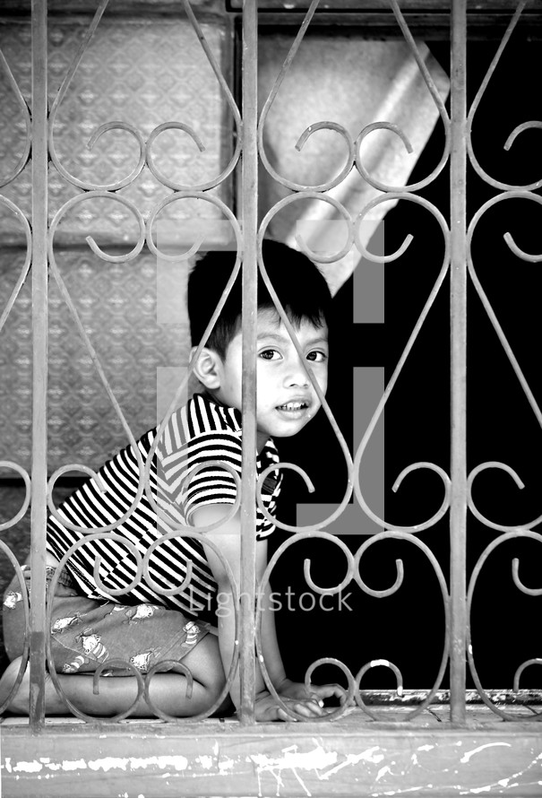 Child playing behind iron window