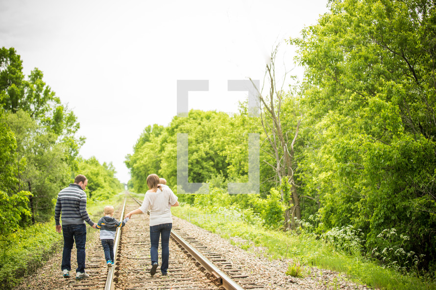 family walking on train tracks holding hands 