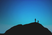 silhouettes standing on a mountaintop 