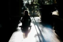 a child sitting in sunbeams with back to the camera 
