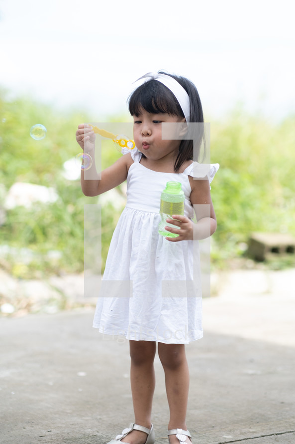 toddler girl blowing bubbles outdoors 