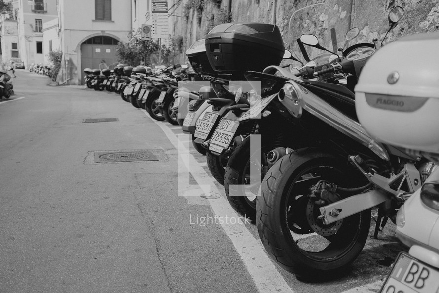 motorcycles and Vespas parked along a street in Italy 