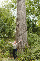 woman standing alone in a forest with open arms rejoicing 