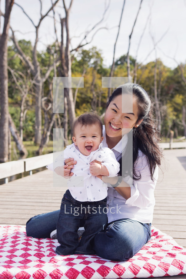 mother and infant son on a blanket outdoors 