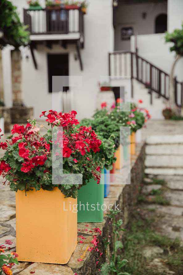 Colorful containers of flowers on a stone wall.