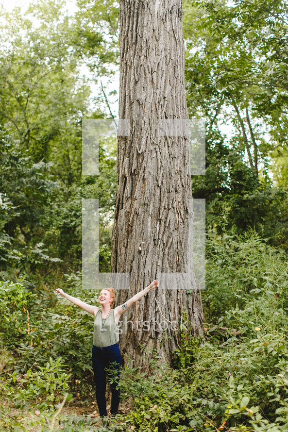 woman standing alone in a forest with open arms rejoicing 