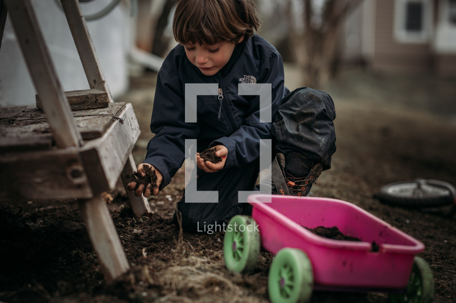 boy playing in dirt in the backyard 